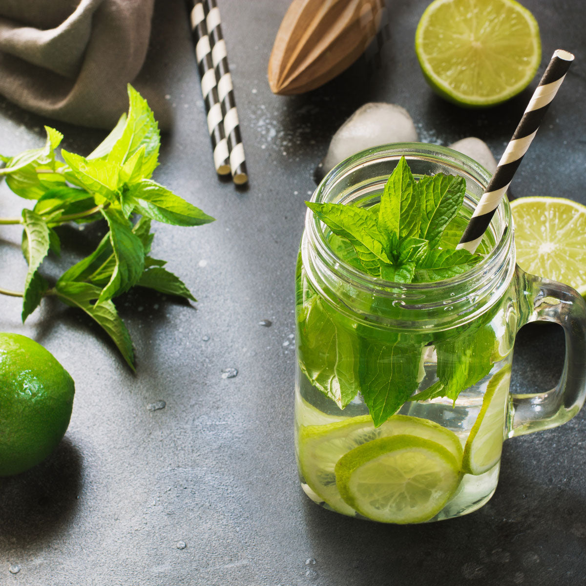 A glass jar containing a Mojito drink with peppermint in it 
